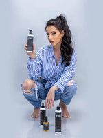 Зареди изображението в галерията, Млада жена стойка на колене, държаща флакон F-Expert спрей за обем, с козметични продукти наоколо.