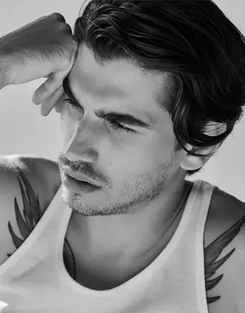 Мъж с къса прическа и татуировки, използващи стилизиращи продукти за мъже.